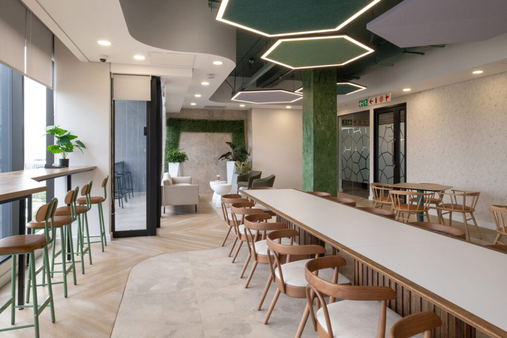 Open-plan canteen with long tables, cushioned seating and hexagonal ceiling lighting in BASF workspace