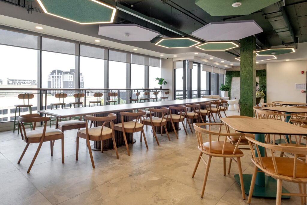 Open-plan canteen with long tables, wooden chairs and hexagonal lighting in BASF office