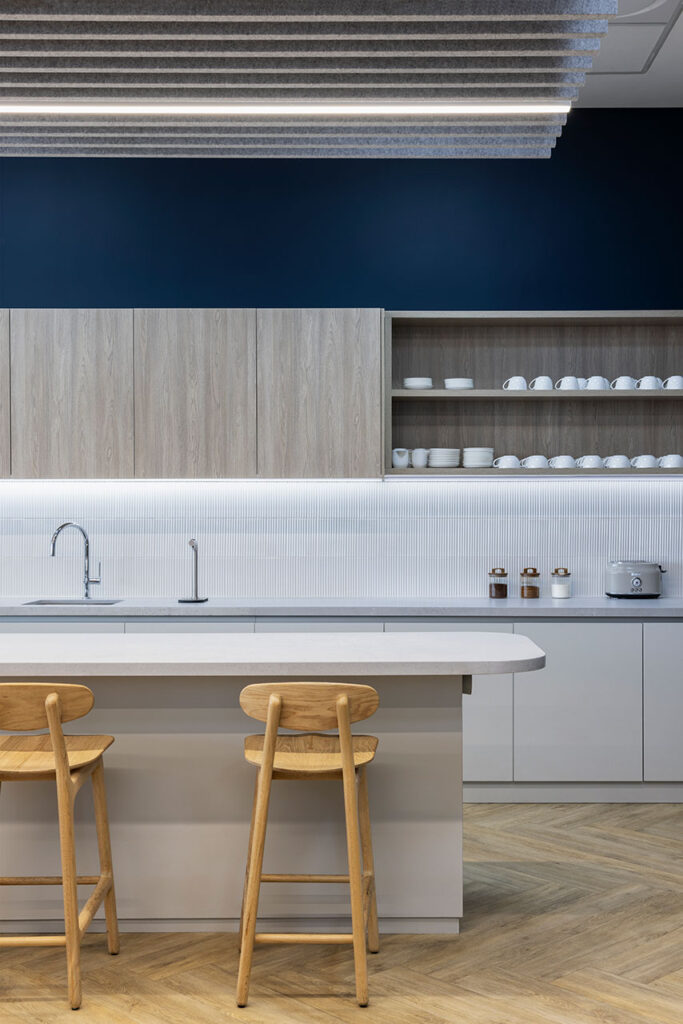 Canteen with wooden bar stools and kitchen area in Pinsent Masons office in Rosebank