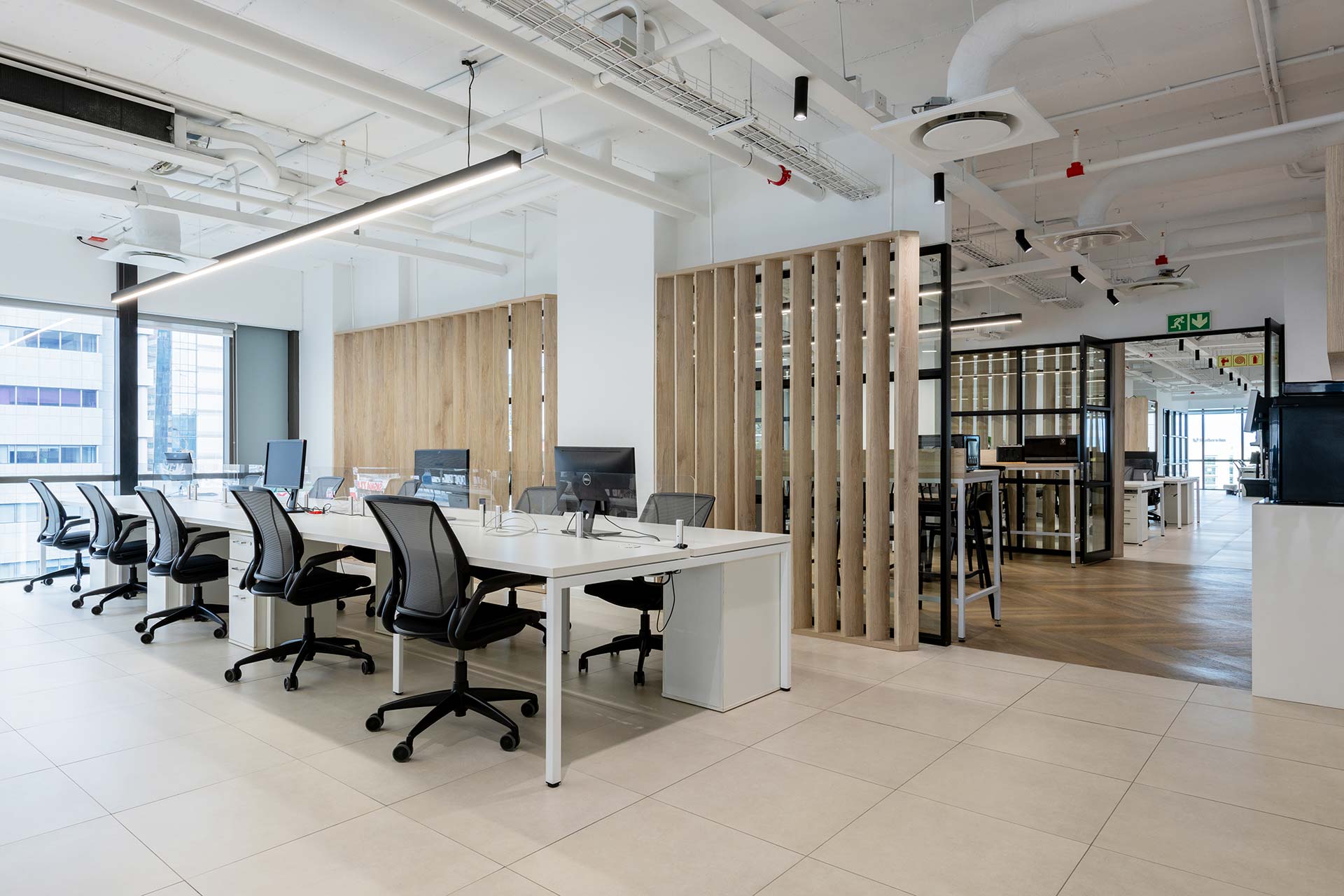 Workstations with ergonomic chairs and wooden panel walls in Superbalist office in Cape Town