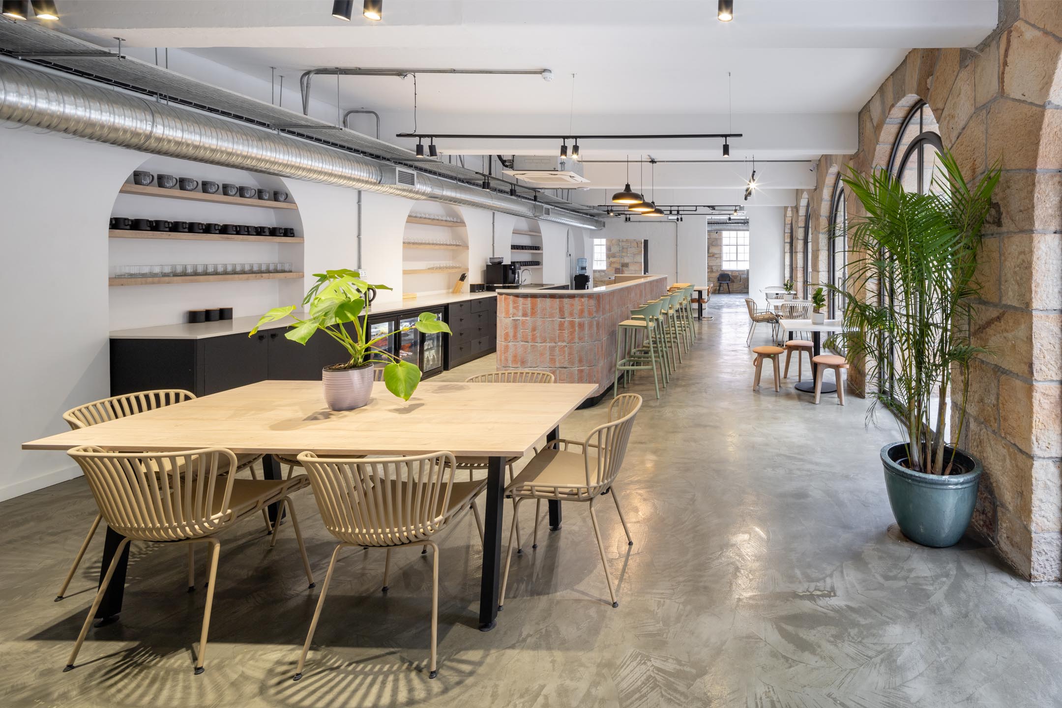 Staff canteen area with long dining table wishbone style chairs stone archway and bespoke furniture services