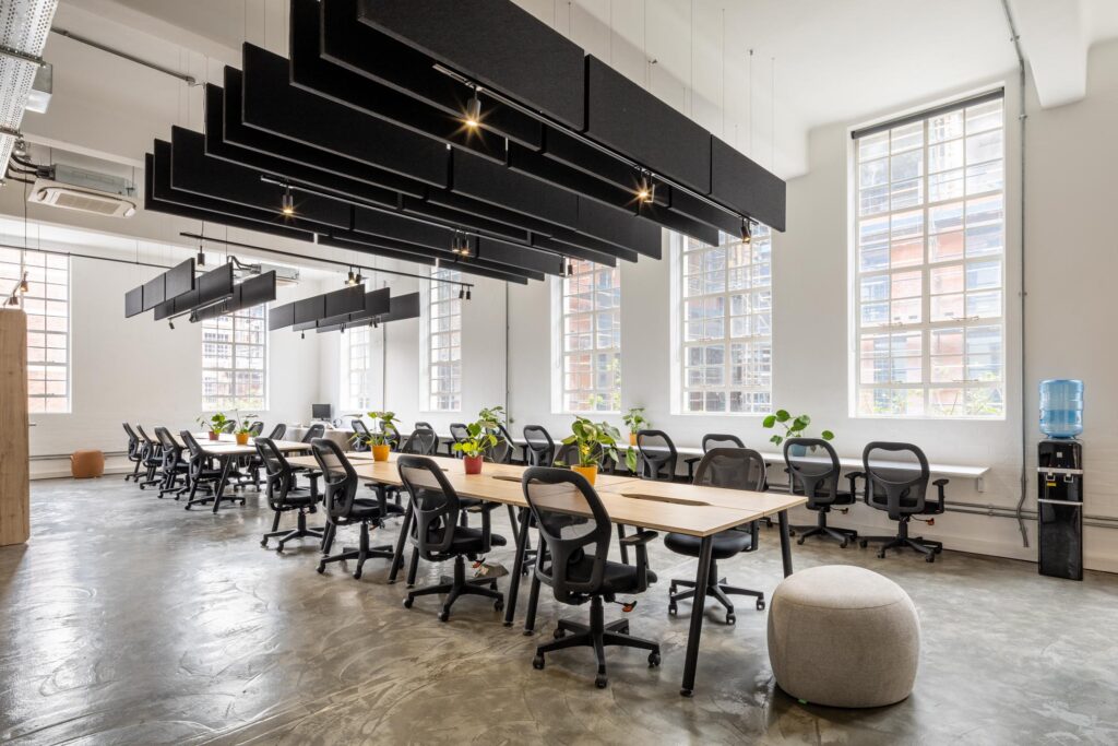 Open plan training room with long meeting tables task chairs acoustic panels and natural light for workplace furniture solutions
