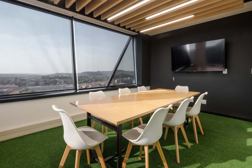 BOB Group office boardroom with modern tables and chairs, green AstroTurf flooring, contemporary lighting and furniture designed to suit the brand