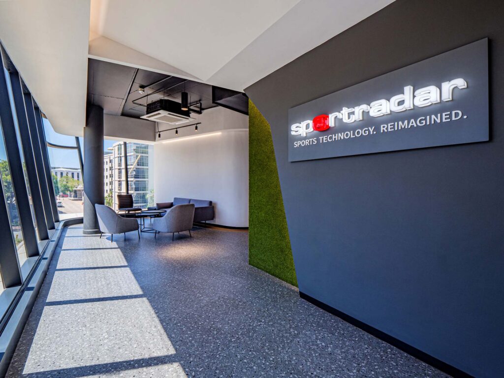 Sportradar office reception and waiting area with custom branded furniture, couches, visitor chairs, a green feature wall and branded signage