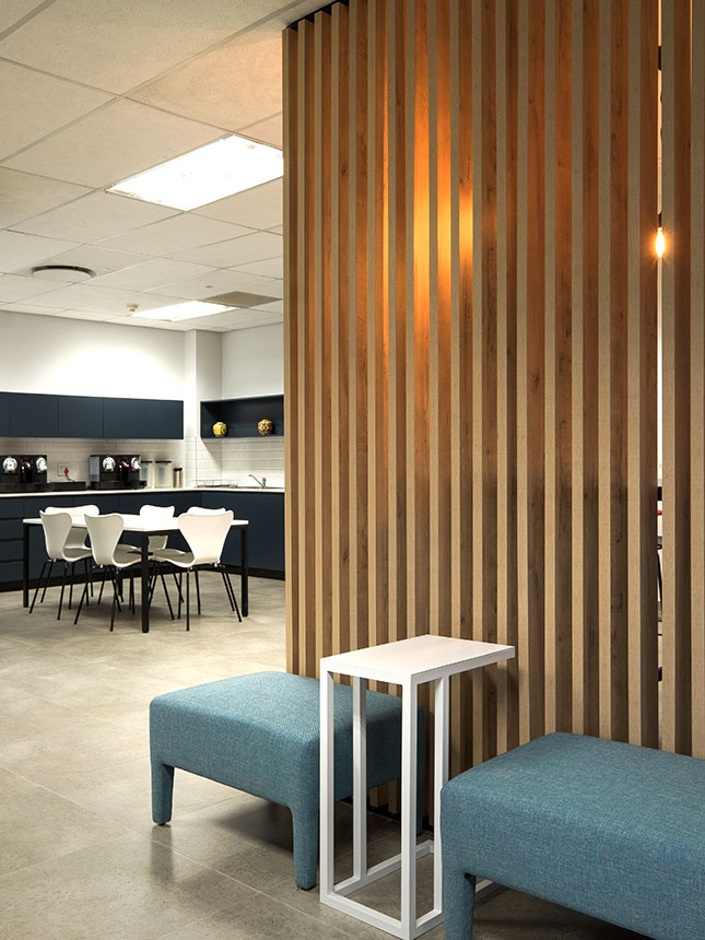 Atlas Copco South Africa modern collaborative workspace with ottoman seating and laptop table, canteen in background