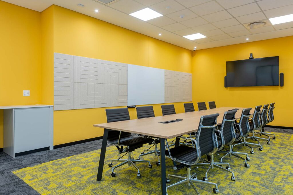 Call centre boardroom with ergonomic seating, large timber meeting table and custom-coloured acoustic panels, showcasing premium FF&E furniture procurement