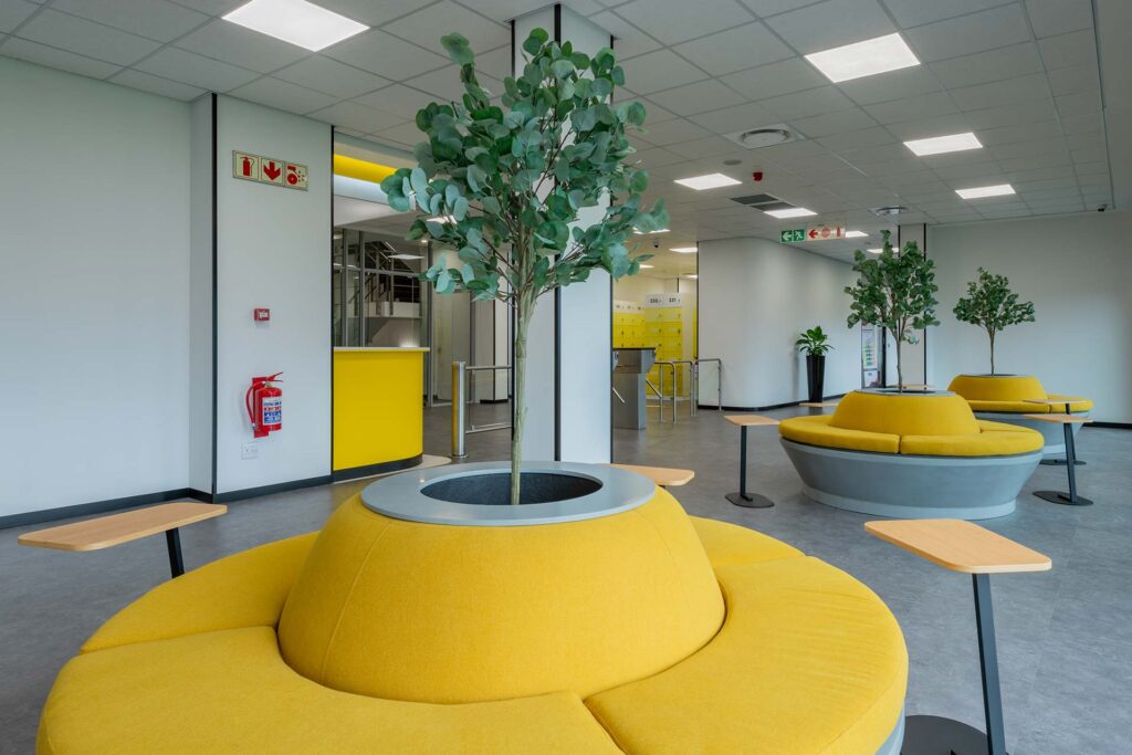 Call centre reception area with bright yellow booth seating and laptop tables, showcasing flexible workplace furniture solutions