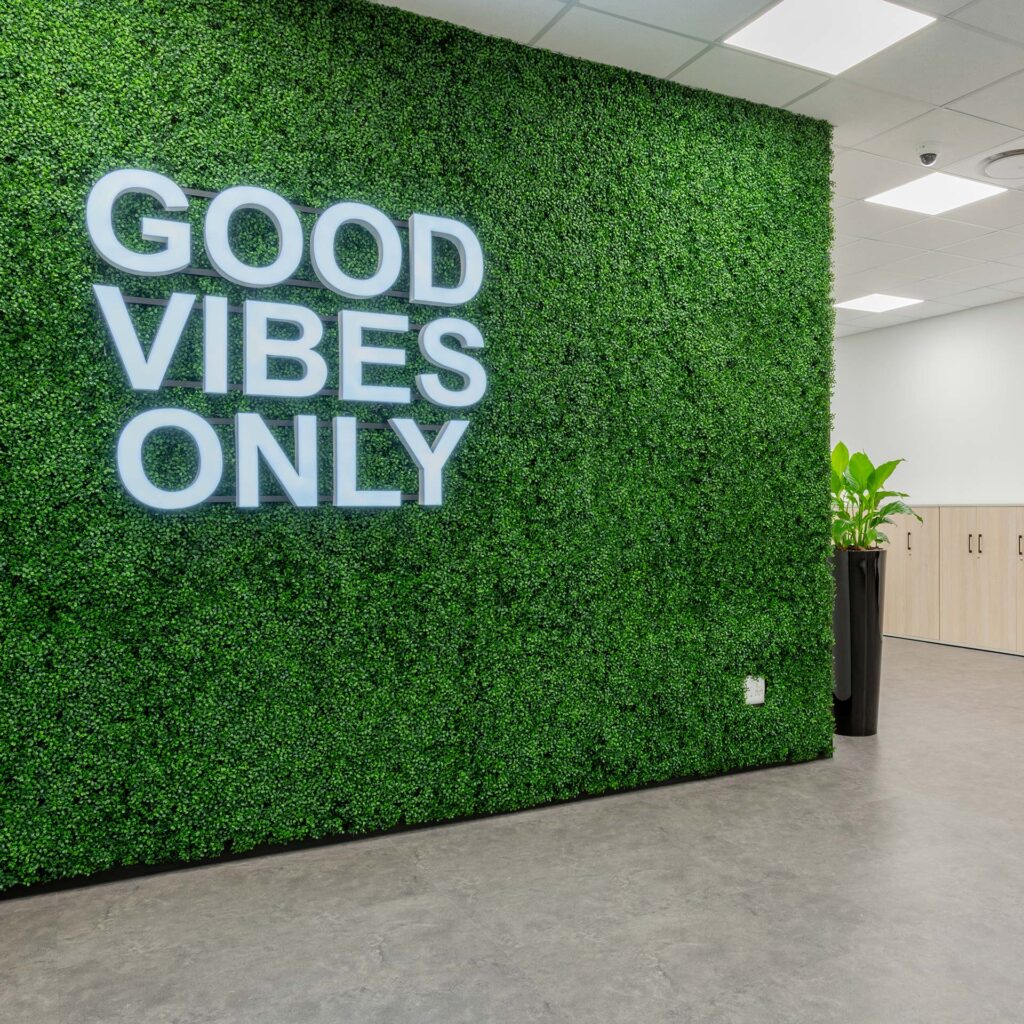 Call centre office feature wall with green planting and “Good Vibes” signage, creating a vibrant and engaging workplace interior