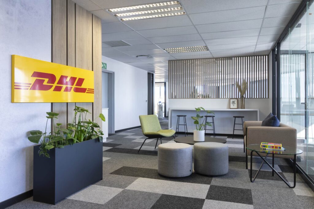 Custom-designed office furniture for DHL SA, featuring hybrid seating, collaborative areas, and glass coffee tables.