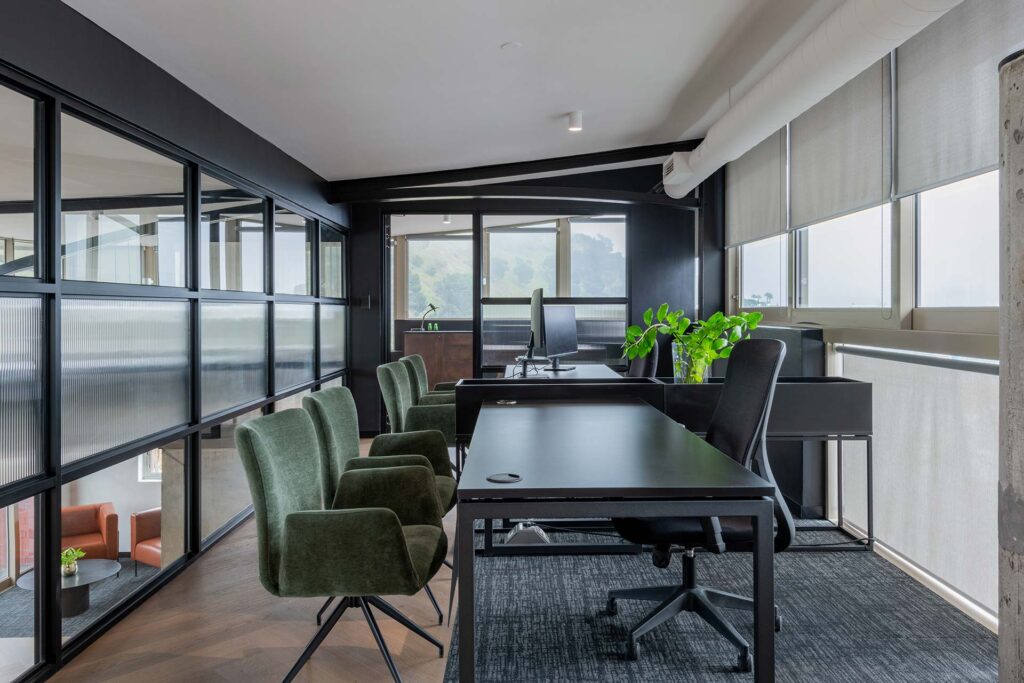 Lion Capital Cape Town meeting room with modern black desks, box planters and soft green armchairs, showcasing premium office furniture solutions