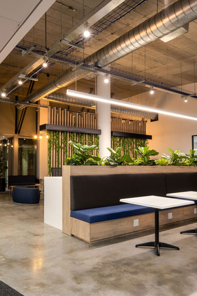 Mazars' modern commercial office interior features a green wall, custom bench, and canteen seating.