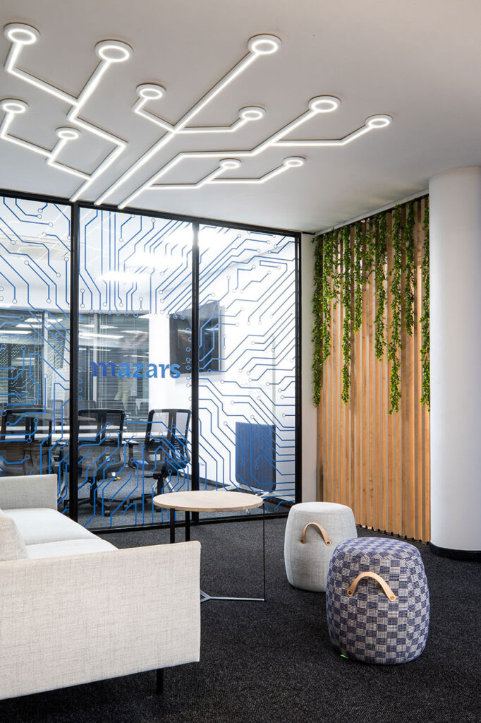 Modern commercial furniture for Mazars office: ottomans, fabric couch, coffee tables.