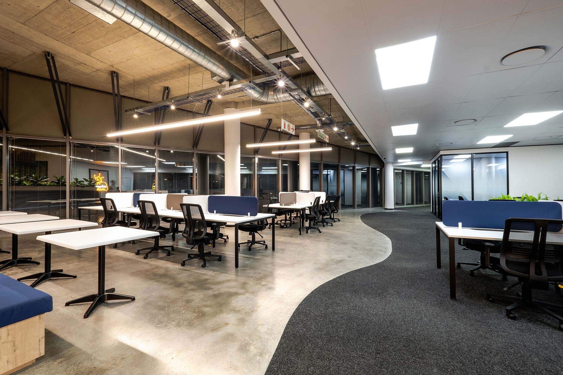 Large open-plan workspace by Design Colab SA, featuring shared desks, colorful screen partitions, and ergonomic office chairs.