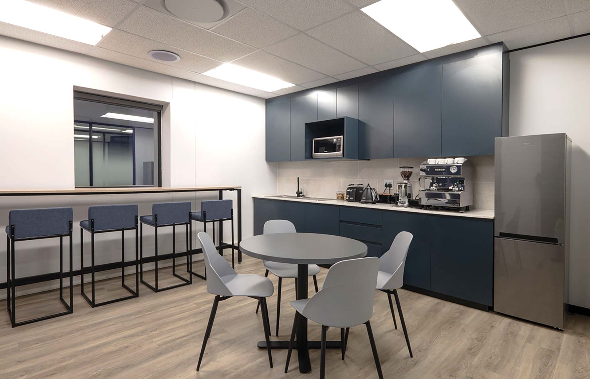 One Vision Pretoria corporate canteen, featuring a kitchen, barstools, and tables in brand colors.