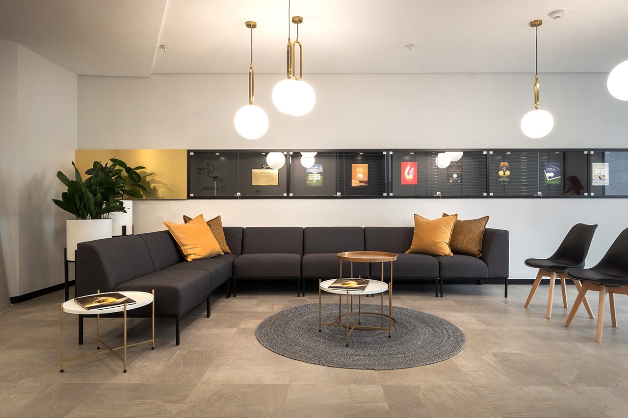 Modern commercial furniture: a large black couch with custom cushions, visitor chairs, and a gold design.