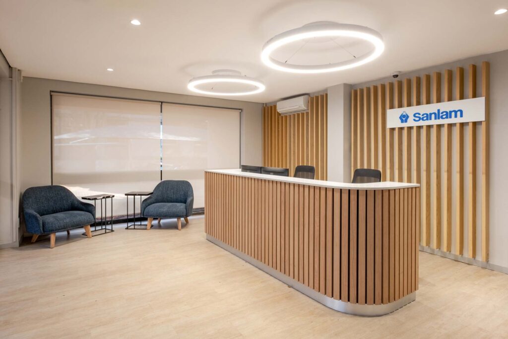 Sanlam Houghton reception with custom timber desk and soft seating, showcasing premium office furniture solutions