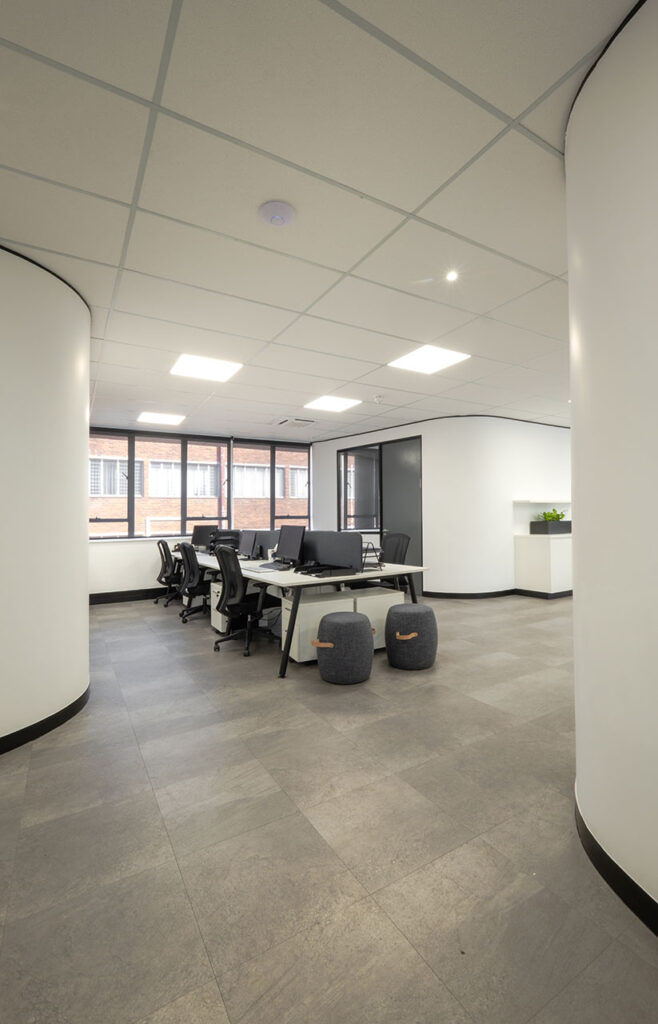 Snowsoft minimalist office with white shared desks, ergonomic office chairs and ottomans for flexible seating, showcasing adaptable workplace furniture solutions