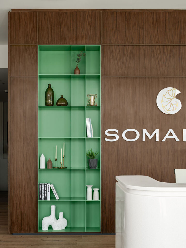 Soma Bay Cairo office reception with high-gloss desk, custom green wall shelving and branded décor, showcasing bespoke FF&E procurement