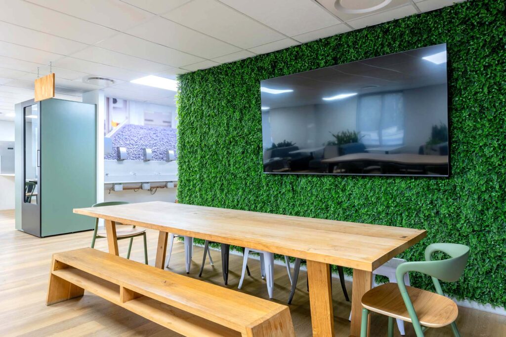United Exports Paarl office canteen with green wall feature, timber bench seating, tables and acoustic phone booth, showcasing FF&E procurement.