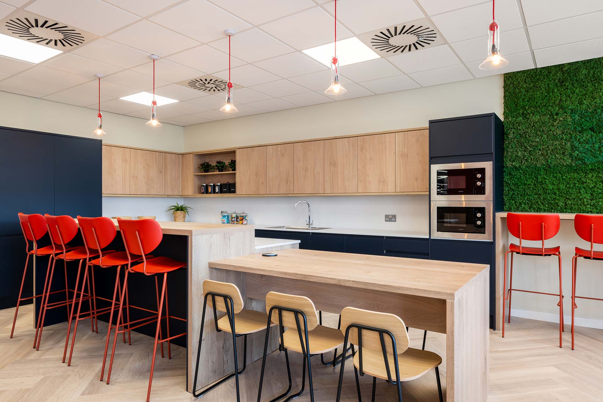 British Airways Euroflyer London office canteen with red bar stools, timber tables, kitchenette cabinetry and contemporary lighting, showcasing FF&E procurement