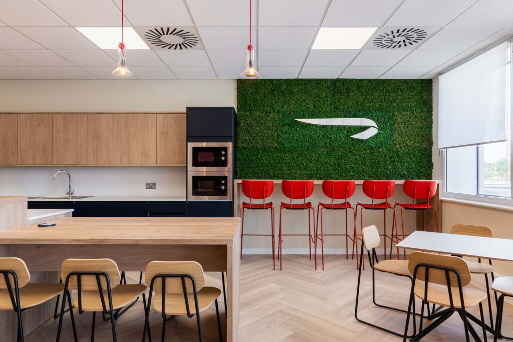 British Airways Euroflyer London office canteen with contemporary timber furniture, kitchenette and red bar stools, showcasing commercial FF&E procurement